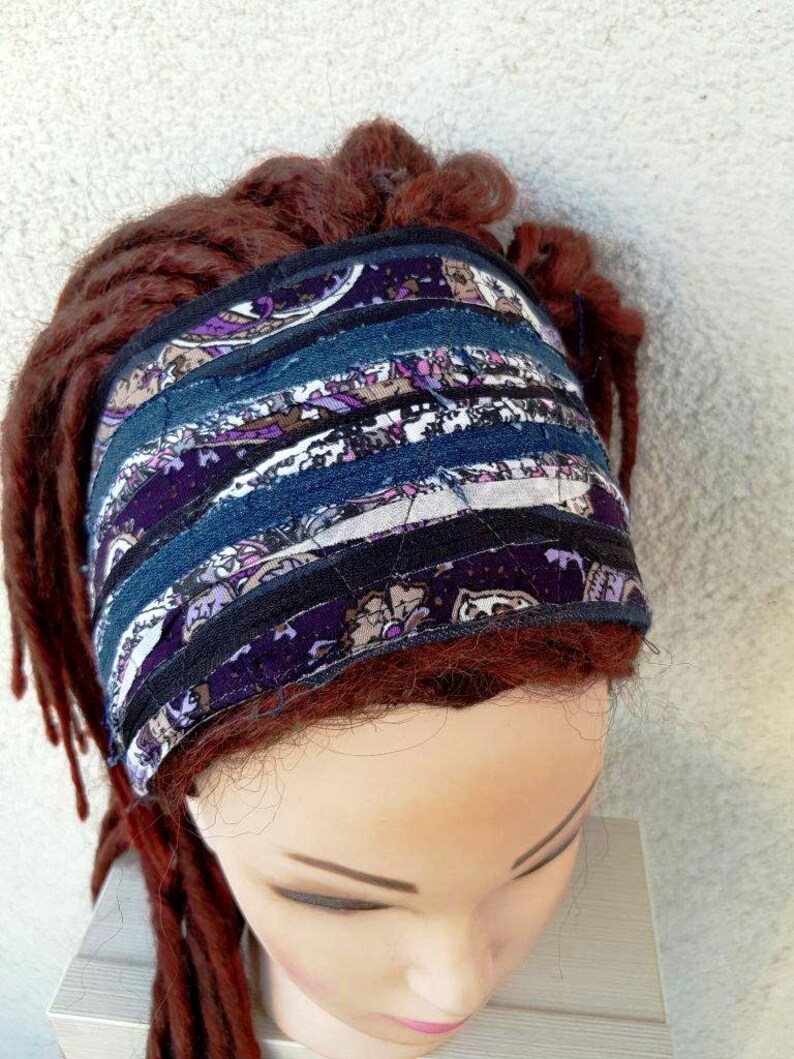 May include: A purple and blue patterned headband made from fabric scraps. The headband is worn on a mannequin with red hair.