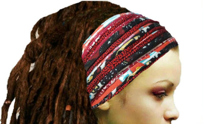 May include: A wide, multi-layered fabric headband featuring a vibrant pattern of red, black, white, and blue colors. The accessory is constructed from several horizontal bands of fabric that create a gathered, textured appearance across the forehead.