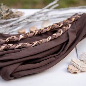 May include: A dark brown fabric headband featuring a decorative braided accent across the top. The braid is composed of three distinct strands in shades of dark brown, light tan, and a textured dark brown pattern, creating a layered appearance.