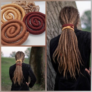 May include: Three flexible, fabric-wrapped spiral hair ties in mustard yellow, light brown, and deep burgundy. These long, cylindrical accessories are shown coiled individually and wrapped around a thick ponytail of long, light brown dreadlocks.