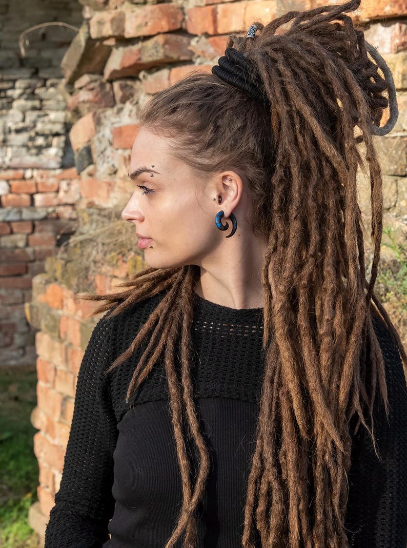 K&ouml;nnte beinhalten: Ein dunkelblauer Spiral-Ohrschmuck, der in einem gepiercten Ohrl&auml;ppchen getragen wird. Das Schmuckst&uuml;ck hat ein geschwungenes, spitz zulaufendes Design mit glatter Oberfl&auml;che und zeigt einen tiefblauen Farbton mit dezenten dunklen Wirbeln.