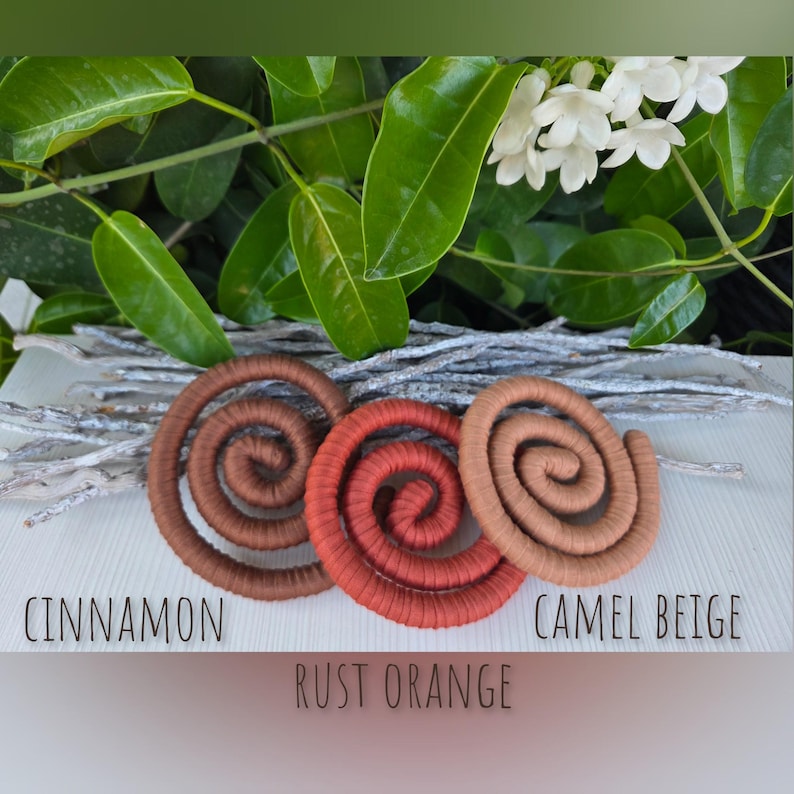 Puede incluir: Tres objetos decorativos en forma de espiral en colores canela, naranja &oacute;xido y beige camello. Cada pieza presenta un dise&ntilde;o enrollado con una superficie texturizada. Las etiquetas Cinnamon, Rust Orange y Camel Beige aparecen impresas debajo.
