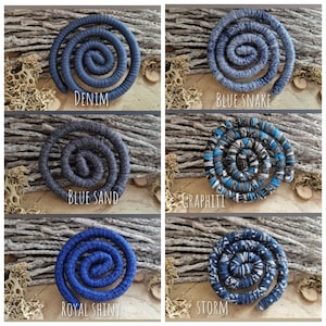 May include: Six spiral-shaped hair accessories in various shades of blue and gray. Each accessory is labeled with a descriptive name: Denim, Blue Snake, Blue Sand, Graphiti, Royal Shiny, and Storm. The accessories are displayed on a textured, neutral background.