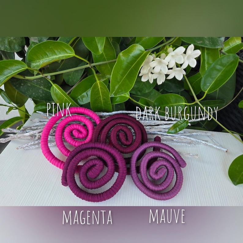 Puede incluir: Cuatro adornos en forma de espiral envueltos en tela en rosa, burdeos oscuro, magenta y malva. Las etiquetas de texto Pink, Dark Burgundy, Magenta y Mauve est&aacute;n colocadas cerca de cada espiral. Las espirales est&aacute;n sobre una superficie blanca.