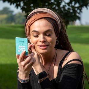 K&ouml;nnte beinhalten: Eine Person mit braunen Dreadlocks und einem braunen Stirnband h&auml;lt eine blaue Karte mit dem Text "Around or you may" in Wei&szlig;. Die Karte ist Teil eines Kartendecks.