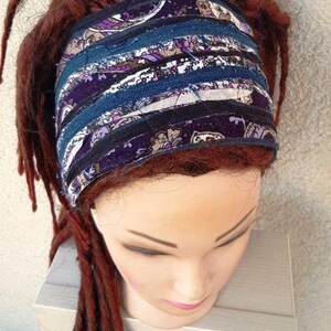 May include: A purple and blue patterned headband made of fabric strips. The headband is worn on a mannequin with long, dark red dreadlocks.
