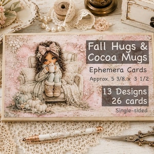 Op de afbeelding: Een rechthoekige doos met ephemera-kaarten getiteld Fall Hugs & Cocoa Mugs, met een illustratie van een meisje met een strik dat een mok vasthoudt. De doos bevat 13 ontwerpen, 26 enkelzijdige kaarten en meet ongeveer 13,65 x 8,89 cm.
