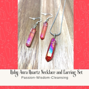 May include: A set of ruby aura quartz jewelry featuring a necklace and earrings. The necklace and earrings have silver chains and feature a long, pointed, iridescent ruby aura quartz crystal.