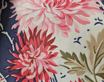 May include: Close-up of a fabric with a floral pattern. The design features large pink and red chrysanthemum flowers, green leaves, and white accents on a navy blue background. The fabric has a vintage or retro aesthetic.