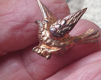 May include: A gold-toned bird brooch with detailed wings and a textured finish.