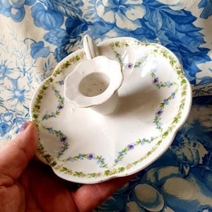 Peut inclure: Bougeoir en porcelaine blanche avec un motif floral. Le bougeoir a un bord festonné et une petite poignée.