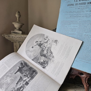 May include: An open book with detailed black and white illustrations, featuring figures in action. A light blue vintage magazine is visible in the background. The scene evokes a sense of history and storytelling.