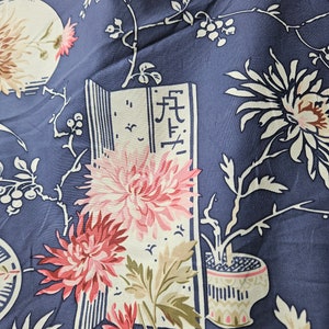 May include: Close-up of a navy blue fabric with a floral pattern. The design features large pink and white chrysanthemums, stylized branches, and a decorative vase. A section of the fabric includes Japanese characters.