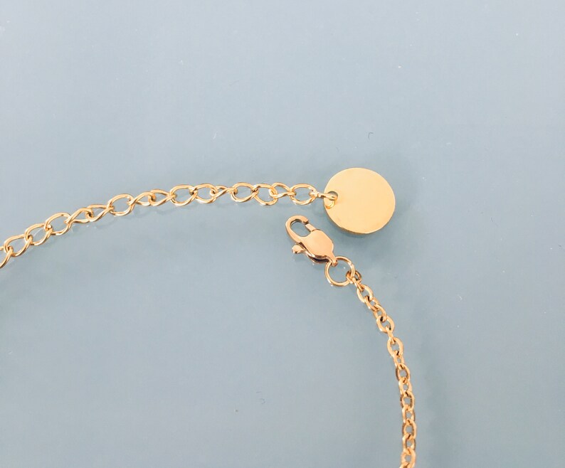 May include: A gold chain bracelet with a round, gold charm. The chain is made of small, linked circles.