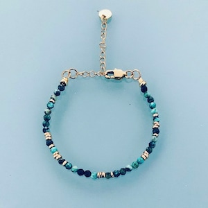 May include: A gold chain bracelet with turquoise and black beads.