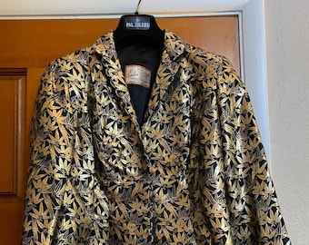May include: A black and gold brocade jacket with a leaf pattern. The jacket has a single button closure and long sleeves. The label on the jacket reads "London Shop".
