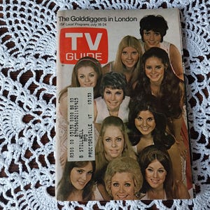 May include: A vintage TV Guide magazine cover featuring a group of women. The cover has the title "The Golddiggers in London" and the TV Guide logo. The background is a white crocheted doily.