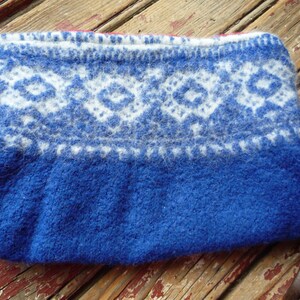 May include: A blue knitted pouch with a white and blue geometric pattern. The pouch is made of a soft, fuzzy material.
