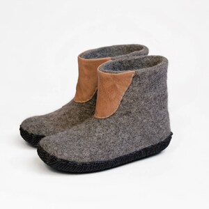 Puede incluir: Botas de fieltro gris con detalles de cuero marr&oacute;n. Las botas tienen una suela oscura y est&aacute;n dise&ntilde;adas para uso en interiores. El fieltro proporciona calidez, ideal para el invierno. Miden aproximadamente 15 cm de alto.