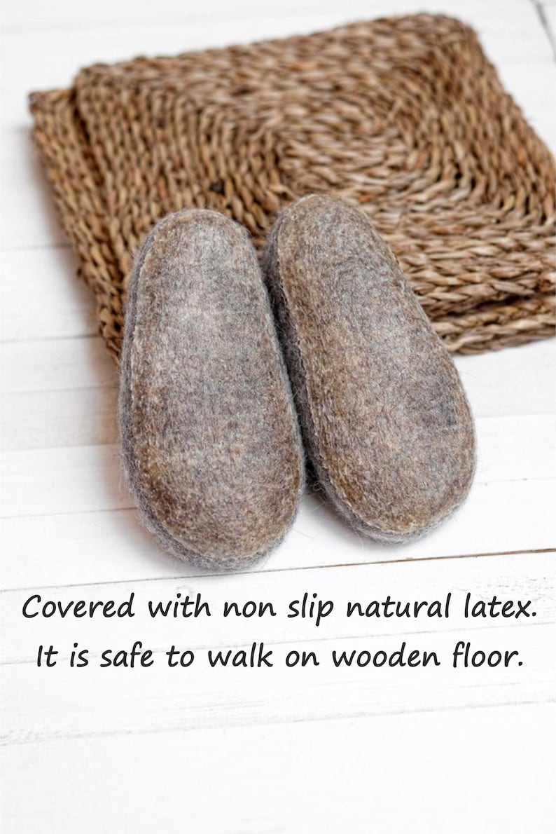May include: A pair of grey felt slippers with a non-slip natural latex sole. The slippers are on a white wooden surface with a woven mat behind them. "Covered with non slip natural latex. It is safe to walk on wooden floor." is written below the slippers.