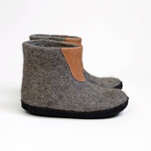 Puede incluir: Botas de fieltro gris con un detalle de cuero marr&oacute;n en el borde superior. Las botas tienen una suela negra y est&aacute;n dise&ntilde;adas para uso en interiores. El fieltro proporciona calidez y comodidad.