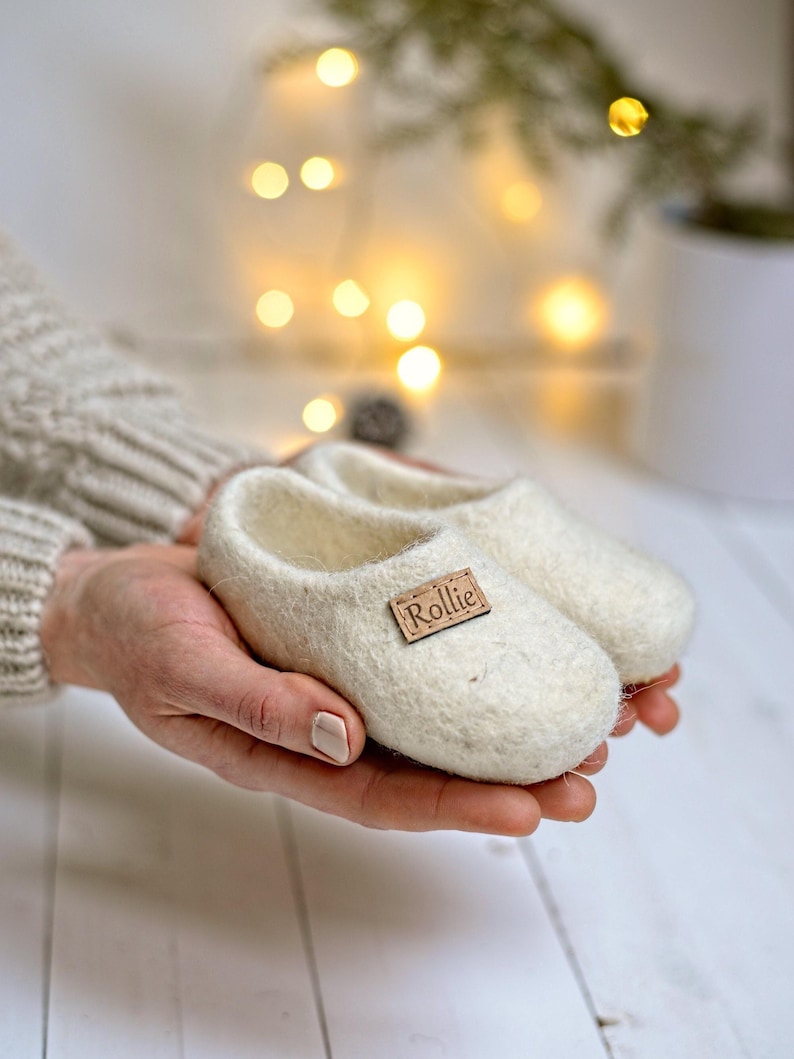May include: A pair of white felt baby booties with a brown leather tag that says "Rollie".