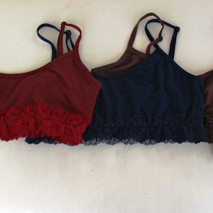 May include: Six different colored bras with lace trim. The bras are in shades of purple, red, blue, brown, and black.