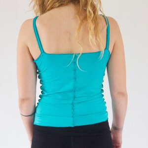 May include: A turquoise tank top with thin straps. The top is made of a stretchy material and has a fitted silhouette.