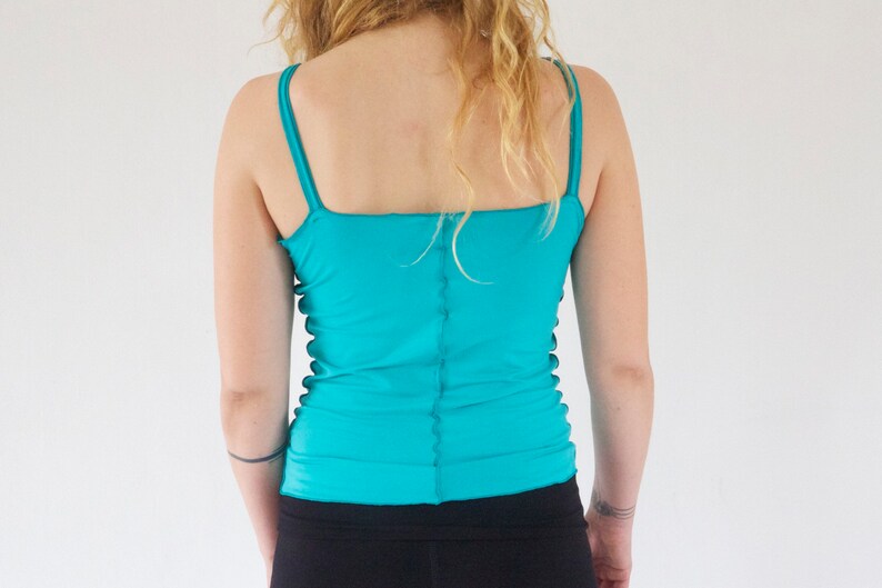 May include: A turquoise tank top with thin straps. The top is made of a stretchy material and has a fitted silhouette.