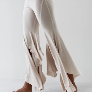 May include: A pair of off-white wide-leg pants with a ruffled hem. The pants are made of a soft, flowing fabric and have a relaxed fit.