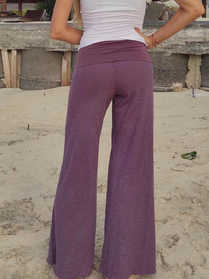 May include: Purple wide-leg pants with a wide waistband. The pants are made of a soft, flowing fabric.
