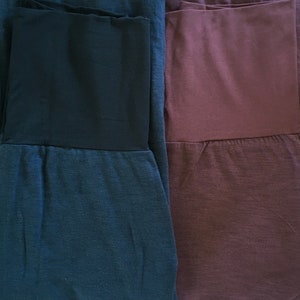 May include: Two pairs of pants, one dark blue and one burgundy, with a contrasting black waistband.