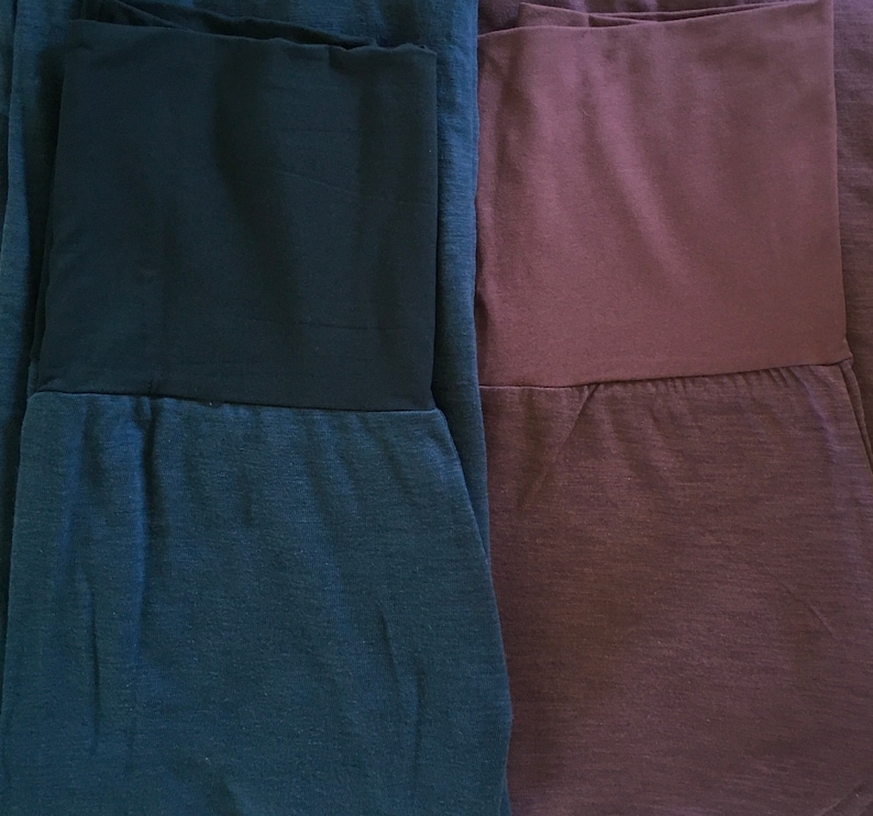 May include: Two pairs of pants, one dark blue and one burgundy, with a contrasting black waistband.