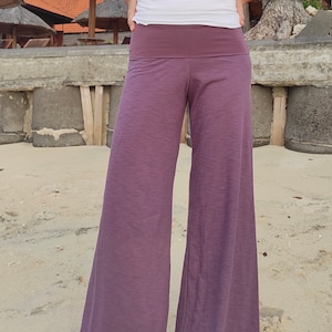 May include: Wide-leg pants in a deep purple color with a wide waistband. The pants are made of a soft, flowing fabric.