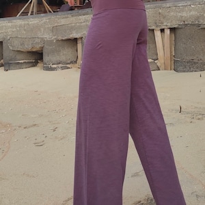 May include: A pair of wide-leg pants in a deep purple color. The pants have a wide waistband and a relaxed fit.