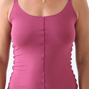 May include: A magenta sleeveless tank top with a raw edge seam down the center front.