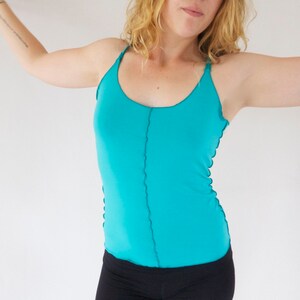 May include: A turquoise tank top with thin straps and a straight neckline. The top has a seam down the center front.