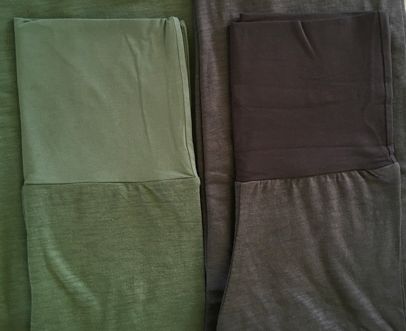 May include: Two pairs of leggings with a contrasting waistband. One pair is green with a dark green waistband, and the other pair is gray with a black waistband.
