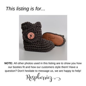 Pode incluir: Um par de sapatinhos de beb&eacute; em crochet cinzento com sola de couro castanho e um bot&atilde;o castanho. Os sapatinhos est&atilde;o sobre um fundo branco.