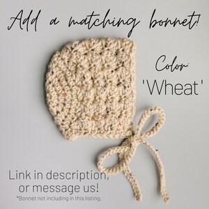 May include: A crocheted baby bonnet in a beige color with a speckled pattern. The bonnet has a tie at the back and the text 'Color: 'Wheat'' is visible in the image.