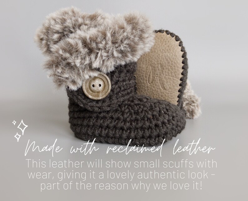 May include: A dark gray crochet baby bootie with a faux fur trim and a button closure. The bootie has a light brown leather sole. The text "Made with reclaimed leather" is visible in the image.