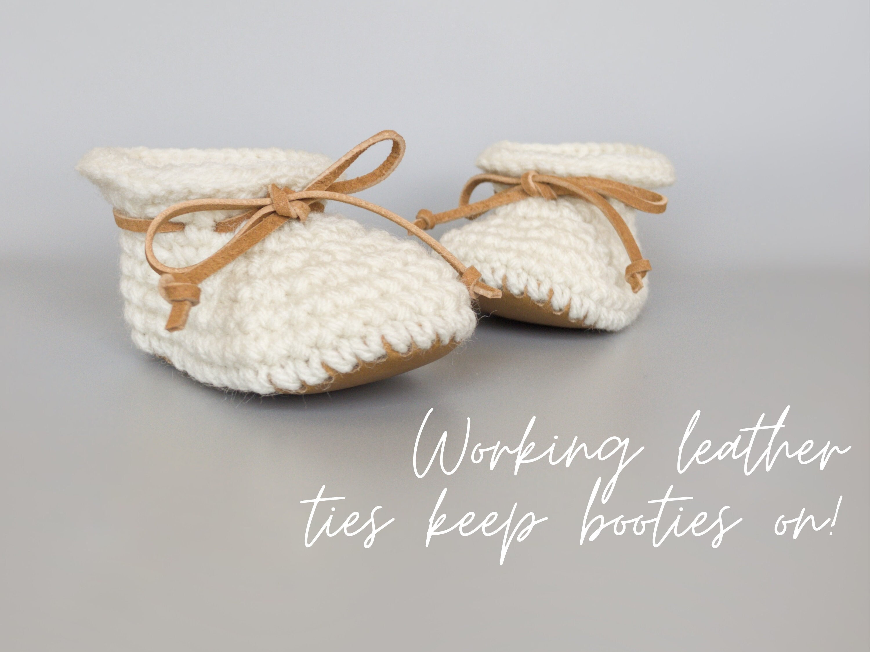 May include: A pair of white crocheted baby booties with brown leather ties. The text "Working leather ties keep booties on!" is written below the booties.