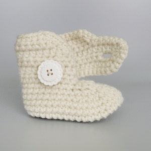 Puede incluir: Zapatillas de beb&eacute; de ganchillo de color crema con un bot&oacute;n blanco.