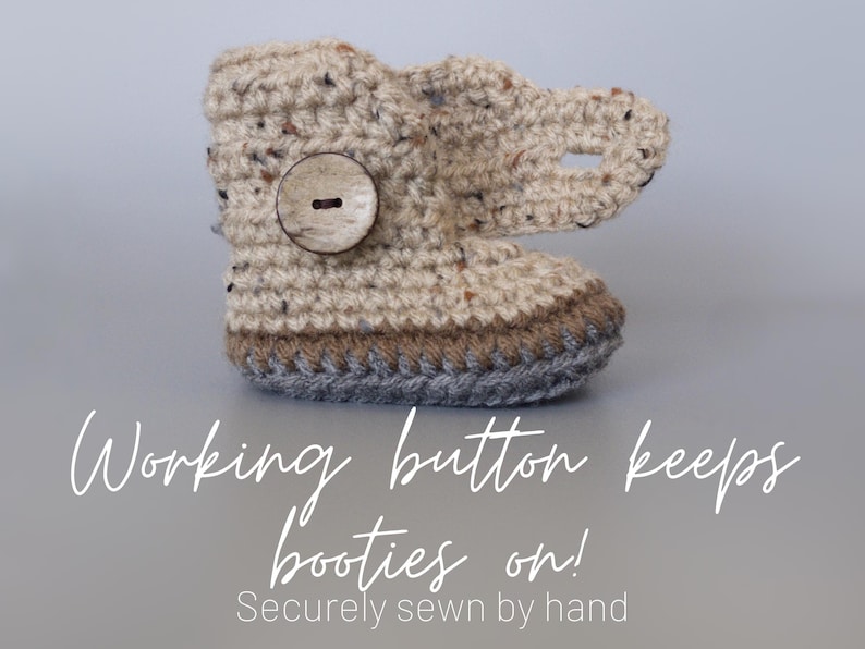 May include: Crocheted baby booties with a brown button and a gray trim. The text "Working button keeps booties on! Securely sewn by hand" is below the booties.