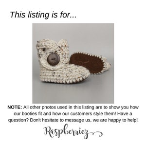 May include: A pair of cream-colored crocheted baby booties with brown button accents. The booties have a suede sole.