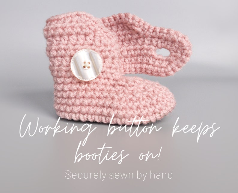 May include: Pink crocheted baby booties with a white button and a loop to keep the booties on. The text "Working button keeps booties on! Securely sewn by hand" is below the booties.