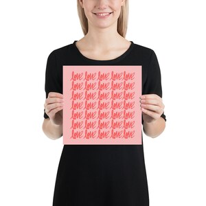 May include: A pink poster with the word "love" repeated in a red, handwritten font.