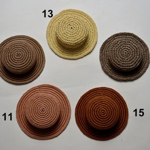 Peut inclure: Cinq chapeaux en crochet de diff&eacute;rentes couleurs, dont le marron, le beige, le brun clair et le rose. Les chapeaux sont dispos&eacute;s en cercle sur un fond blanc.