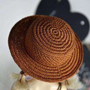 Peut inclure: Un chapeau de soleil en crochet marron &agrave; large bord. Le chapeau est fait d'un fil &eacute;pais et textur&eacute; et a un design simple et classique.