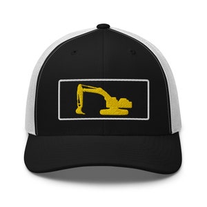 Może przedstawiać: Czarna i biała czapka typu trucker z żółtą naszywką z haftowaną koparką. Czapka ma czarny panel przedni, biały tył z siatki i zakrzywiony daszek. Projekt koparki znajduje się w białej prostokątnej ramce.